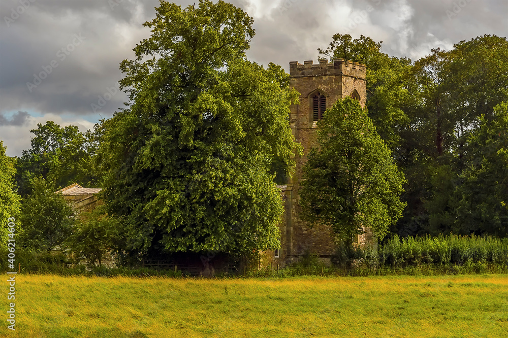 A view across the fields towards a Norman church near Wistow, UK in summertime