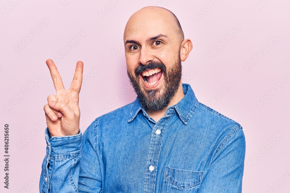 Naklejka premium Young handsome man wearing casual clothes smiling with happy face winking at the camera doing victory sign. number two.