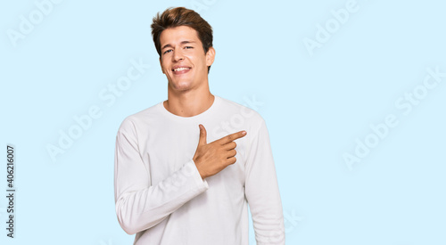 Handsome caucasian man wearing casual white sweater cheerful with a smile on face pointing with hand and finger up to the side with happy and natural expression