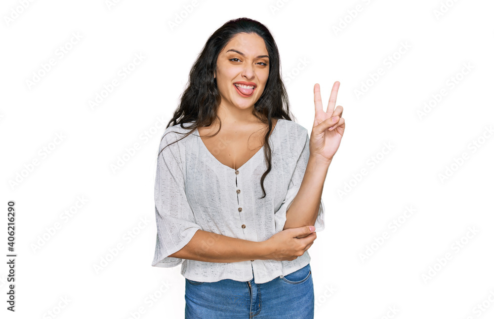 Brunette young woman wearing casual clothes smiling with happy face winking at the camera doing victory sign. number two.
