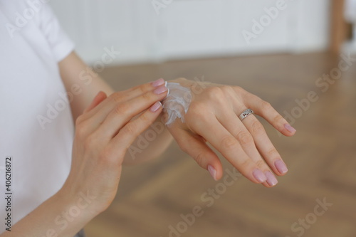 Girl with well-groomed hands and beautiful manicure smears her hands with cream