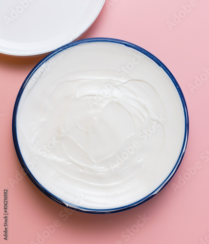cosmetic cream in a blue jar on a pink background. beauty, relaxation and face and body care concept