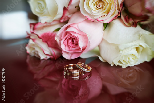 elegant wedding bouquet of white and pink rose flowers. gold wedding rings on the table. preparing for the wedding ceremony