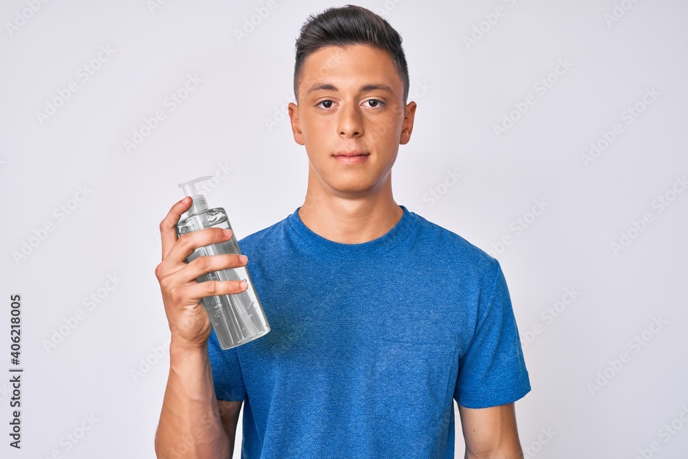 Young hispanic boy using hand sanitizer gel thinking attitude and sober expression looking self confident Young hispanic boy using hand sanitizer gel thinking attitude and sober expression looking self confident