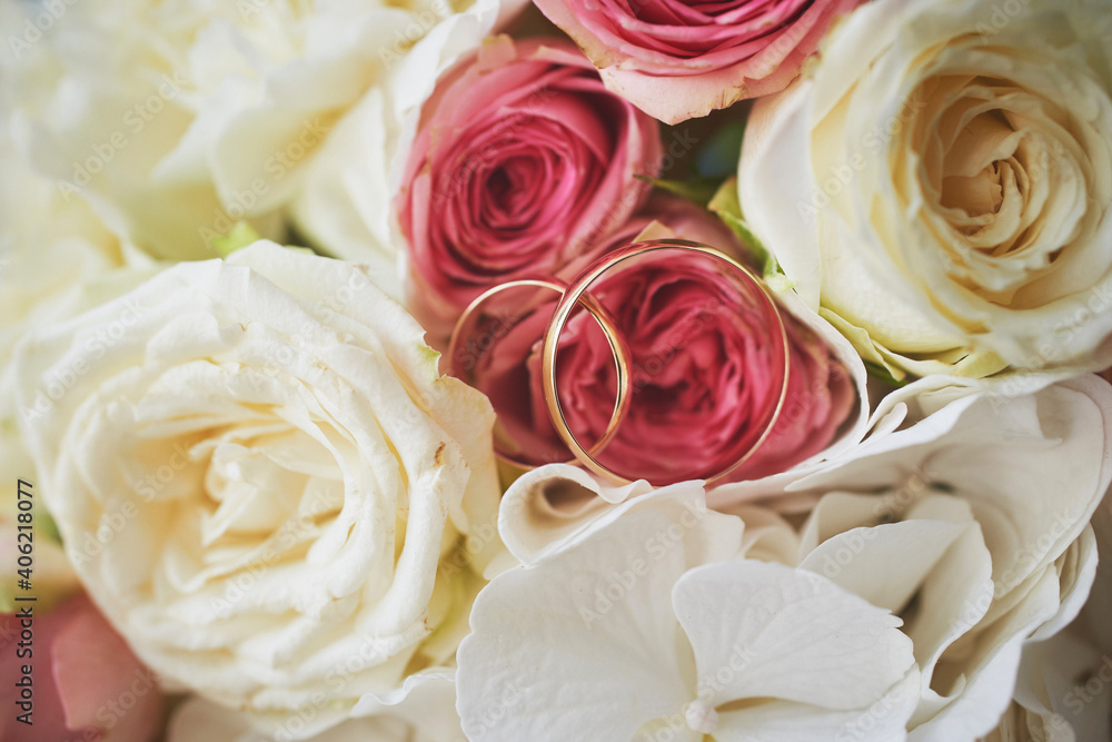 elegant wedding bouquet of white and pink rose flowers. gold wedding rings on the table. preparing for the wedding ceremony