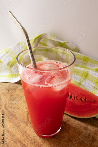 Refreshing watermelon juice with piece of fruit in the background