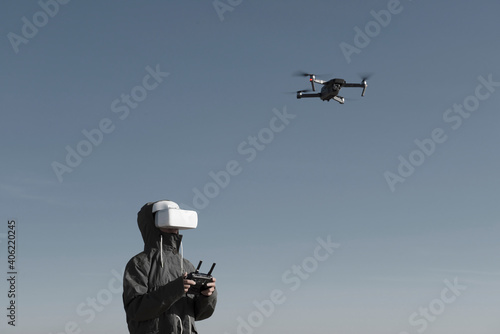 Tourist exploring new places. Drone pilot on nature with quadcopter. Using drone while standing near lake. Young person  with drone and virtual reality viewer.