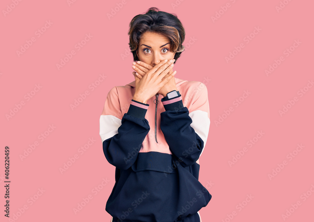 Young beautiful woman wearing sportswear shocked covering mouth with hands for mistake. secret concept. Young beautiful woman wearing sportswear shocked covering mouth with hands for mistake. secret concept.