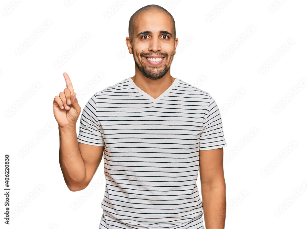 Hispanic adult man wearing casual clothes showing and pointing up with finger number one while smiling confident and happy. Hispanic adult man wearing casual clothes showing and pointing up with finger number one while smiling confident and happy.