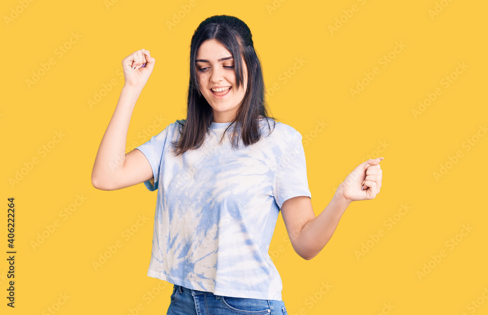 Young beautiful girl wearing casual t shirt dancing happy and cheerful, smiling moving casual and confident listening to music Young beautiful girl wearing casual t shirt dancing happy and cheerful, smiling moving casual and confident listening to music