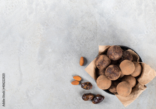 Vegan candies balls of dates, almonds and cocoa in a bowl on a light gray background top view