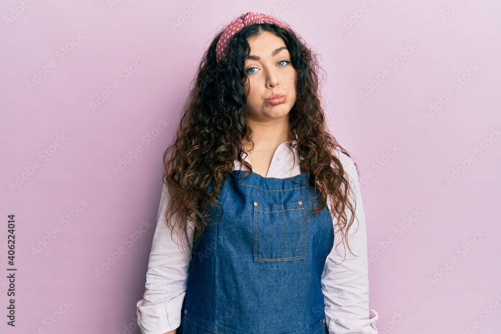 Young brunette woman with curly hair wearing cleaner apron and gloves depressed and worry for distress, crying angry and afraid. sad expression. Young brunette woman with curly hair wearing cleaner apron and gloves depressed and worry for distress, crying angry and afraid. sad expression.