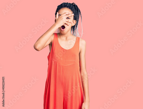 Cute african american girl wearing casual clothes peeking in shock covering face and eyes with hand  looking through fingers with embarrassed expression.