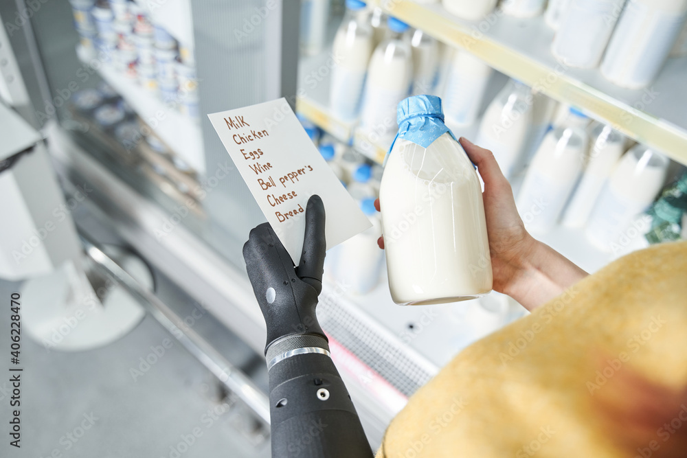 Woman reading shopping list and holding bottle of milk