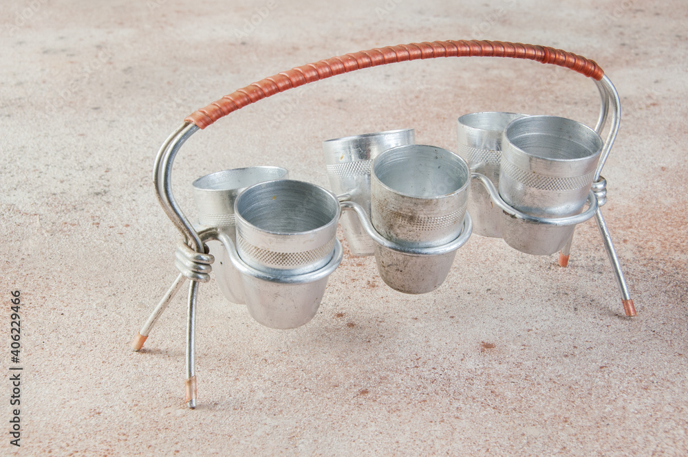 Old aluminum small cups with a stand on concrete background. Old aluminum small cups with a stand on concrete background.