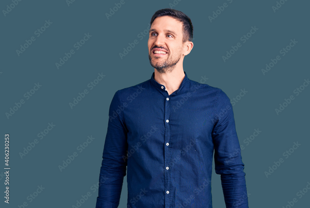 Fototapeta premium Young handsome man wearing casual shirt looking away to side with smile on face, natural expression. laughing confident.