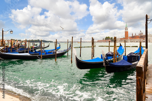 Gondolas dock along the Grand Canal with the Riva di Schiavoni and the Church and island of San Giorgio Maggiore visible in the distance in Venice, Italy. photo