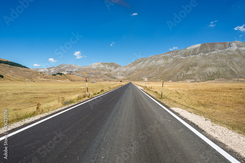 Empty road crossing the fields in Castelluccio di Norcia, Umbria, Italy