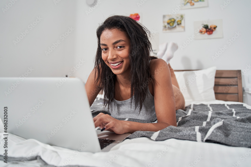 Woman using laptop to video chatting while laying on bed Woman using laptop to video chatting while laying on bed