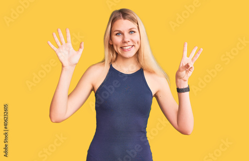 Young beautiful blonde woman wearing casual dress showing and pointing up with fingers number eight while smiling confident and happy.
