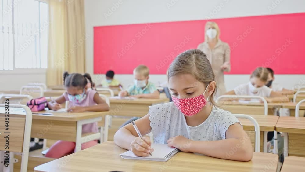 Focused preteen pupils in protective face masks studying in classroom with female teacher. Necessary precautions in coronavirus pandemic. High quality FullHD footage Stock ビデオ | Adobe Stock 