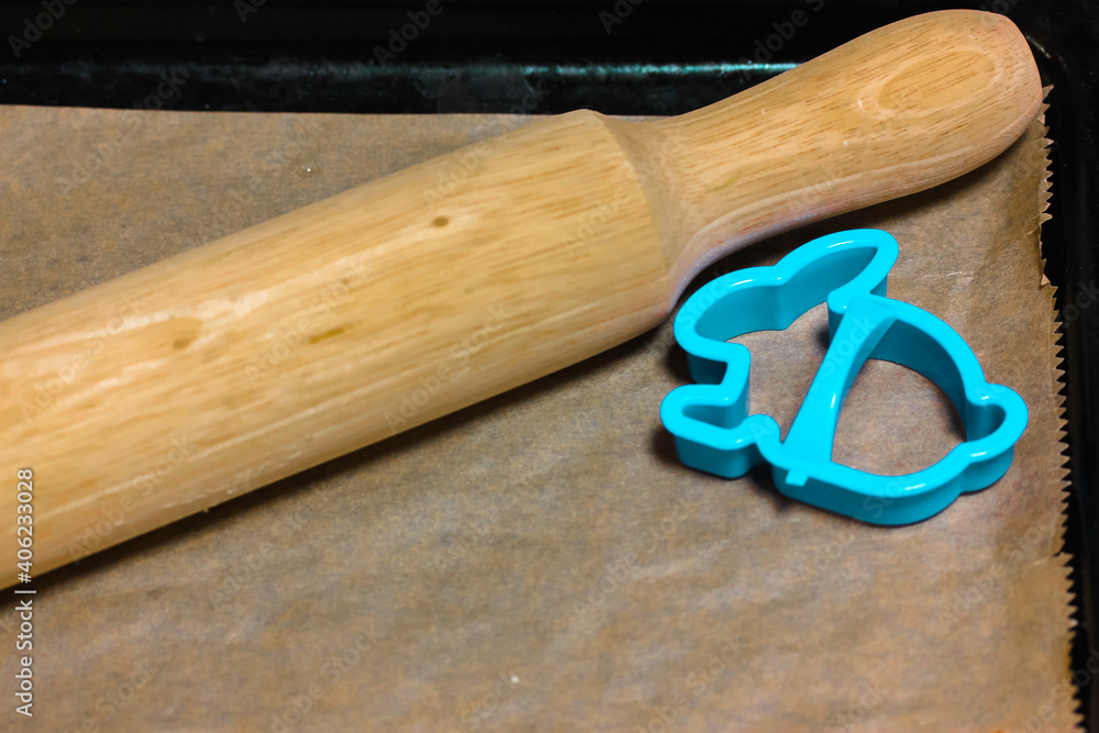 Blue bunny cookie cutter mold on parchment baking paper and wooden rolling pin. Homemade baking, recipes and cooking