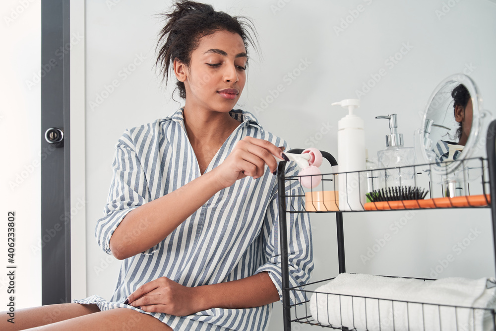 Woman wearing pajamas taking roller massager for legs