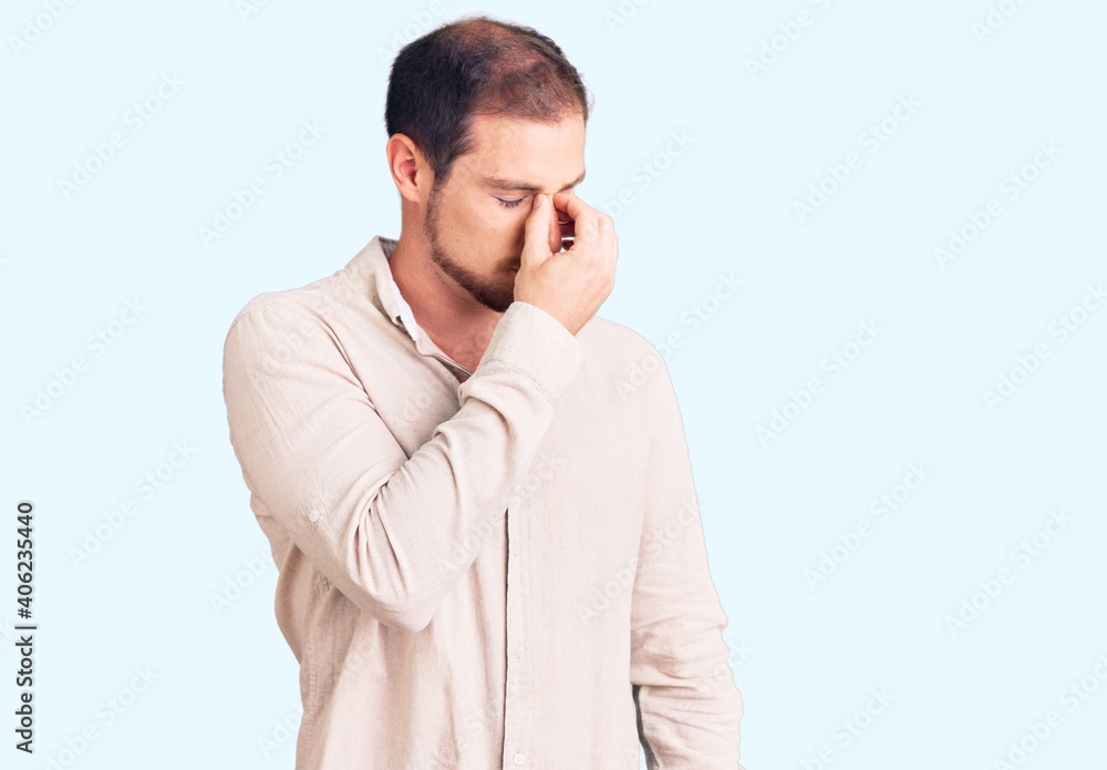 Young handsome caucasian man wearing casual clothes tired rubbing nose and eyes feeling fatigue and headache. stress and frustration concept. Young handsome caucasian man wearing casual clothes tired rubbing nose and eyes feeling fatigue and headache. stress and frustration concept.