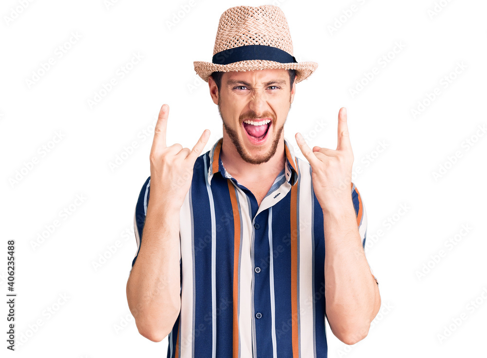 Young handsome caucasian man wearing summer hat shouting with crazy expression doing rock symbol with hands up. music star. heavy concept. Young handsome caucasian man wearing summer hat shouting with crazy expression doing rock symbol with hands up. music star. heavy concept.