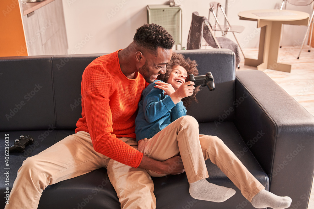 Father tickling his son while spending time together at the room Father tickling his son while spending time together at the room