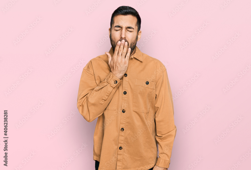 Young hispanic man wearing casual clothes bored yawning tired covering mouth with hand. restless and sleepiness. Young hispanic man wearing casual clothes bored yawning tired covering mouth with hand. restless and sleepiness.