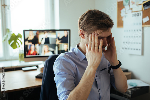 Man Fatigue during home video conference meeting call. Post-work exhaustion from constant face-to-face digital interactions. Working remotely Stay connected during pandemic to combat loneliness photo