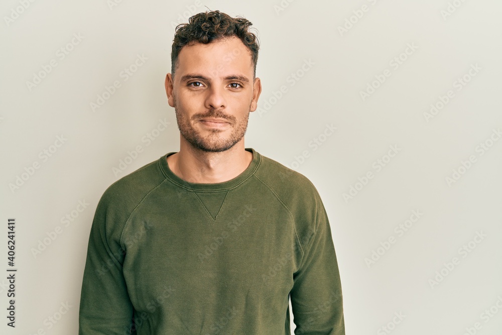 Young hispanic man wearing casual clothes relaxed with serious expression on face. simple and natural looking at the camera. Young hispanic man wearing casual clothes relaxed with serious expression on face. simple and natural looking at the camera.