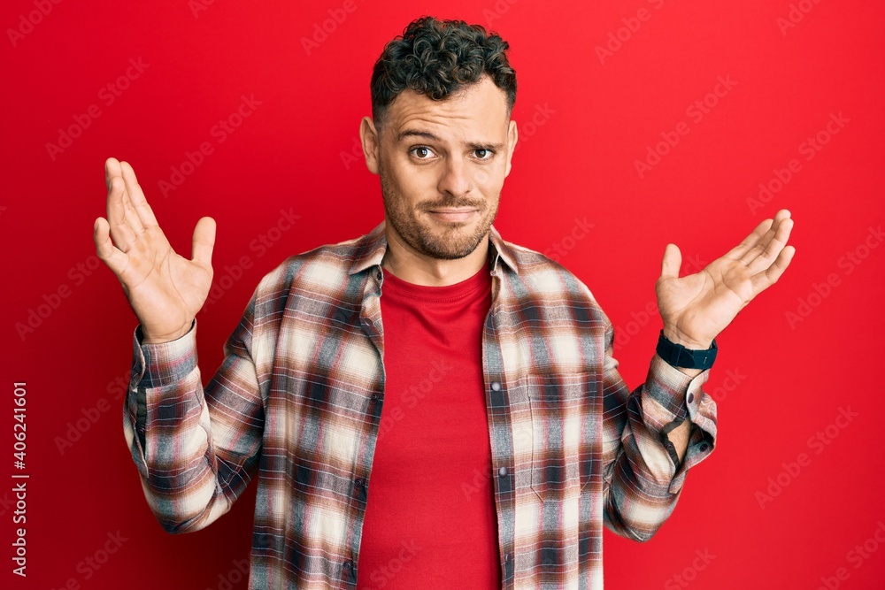 Young hispanic man wearing casual clothes clueless and confused with open arms, no idea and doubtful face. Young hispanic man wearing casual clothes clueless and confused with open arms, no idea and doubtful face.