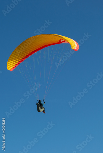 A beautiful view of a paraglide flying gliding on a clear blue sky at the golden hour with a nice wind windy breeze on a sunny day 