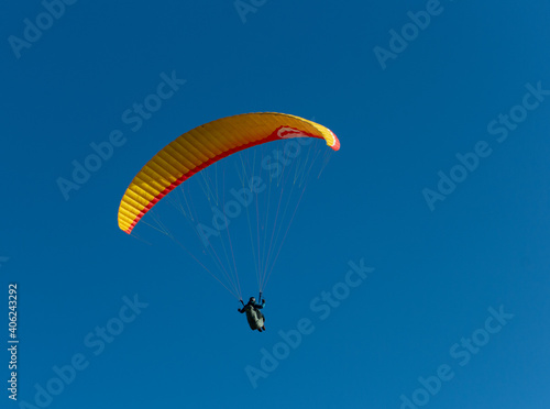 A beautiful view of a paraglide flying gliding on a clear blue sky at the golden hour with a nice wind windy breeze on a sunny day 