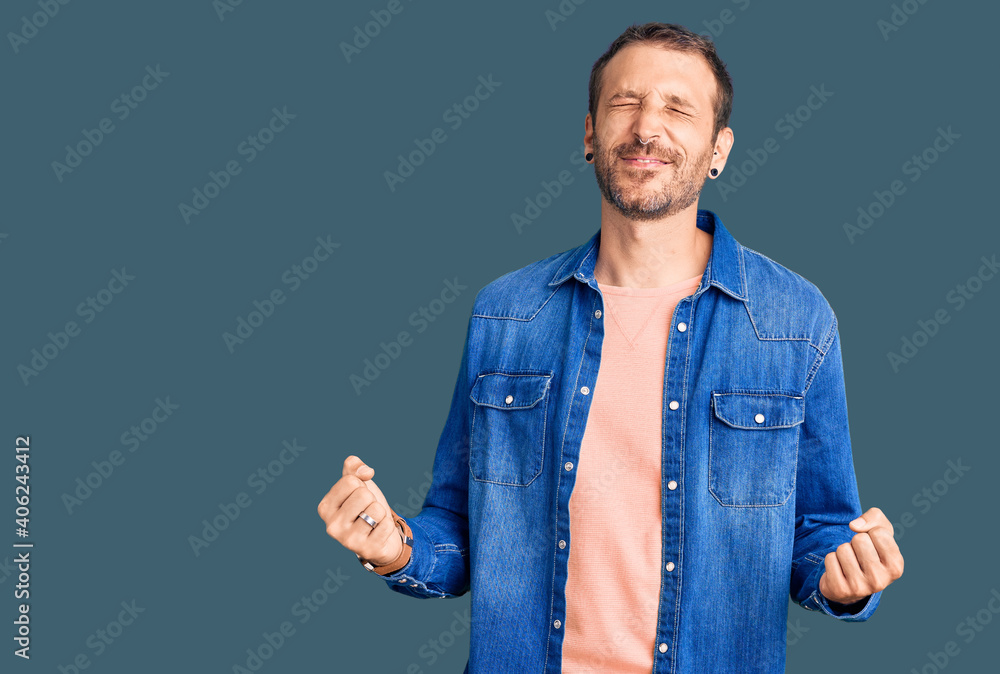 Young handsome man wearing casual clothes very happy and excited doing winner gesture with arms raised, smiling and screaming for success. celebration concept. Young handsome man wearing casual clothes very happy and excited doing winner gesture with arms raised, smiling and screaming for success. celebration concept.