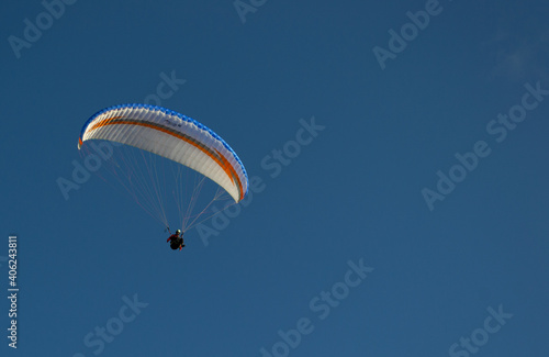 A beautiful view of a paraglide flying gliding on a clear blue sky at the golden hour with a nice wind windy breeze on a sunny day 