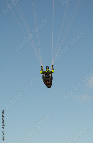 A beautiful view of a paraglide flying gliding on a clear blue sky at the golden hour with a nice wind windy breeze on a sunny day 