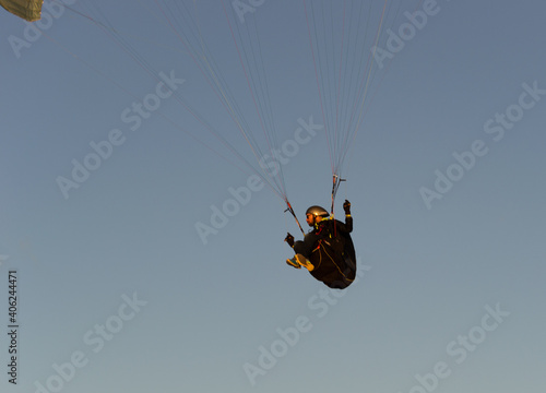 A beautiful view of a paraglide flying gliding on a clear blue sky at the golden hour with a nice wind windy breeze on a sunny day 