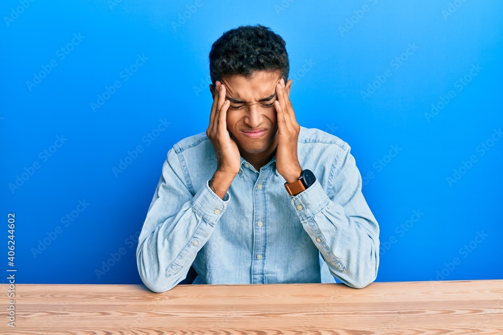 Fototapeta premium Young handsome african american man wearing casual clothes sitting on the table with hand on head, headache because stress. suffering migraine.