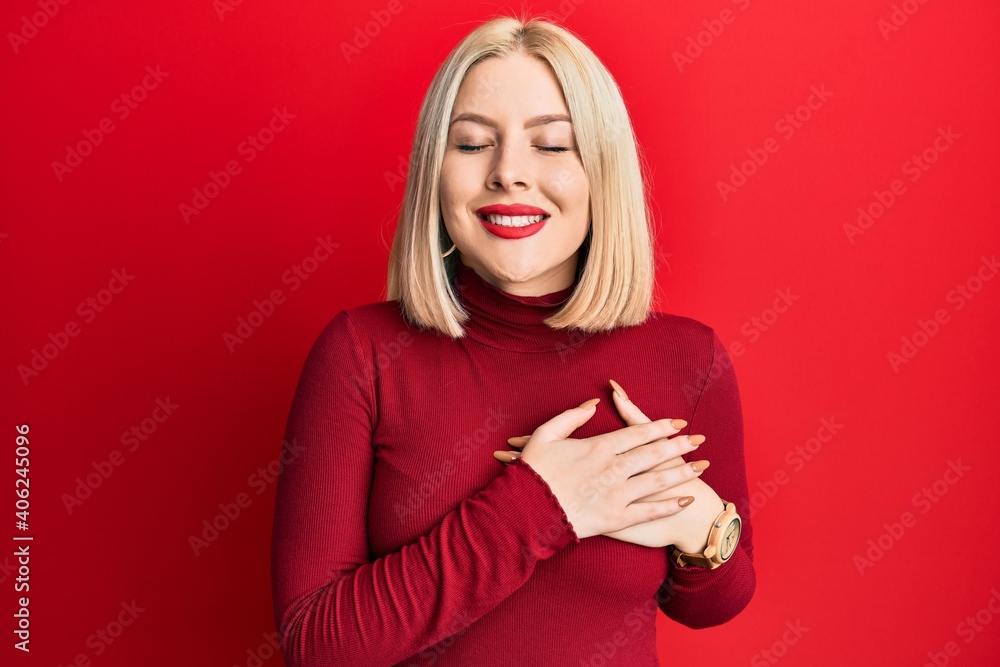 Young blonde woman wearing casual clothes smiling with hands on chest with closed eyes and grateful gesture on face. health concept. Young blonde woman wearing casual clothes smiling with hands on chest with closed eyes and grateful gesture on face. health concept.