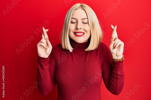 Young blonde woman wearing casual clothes gesturing finger crossed smiling with hope and eyes closed. luck and superstitious concept.