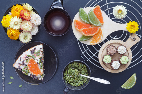 Cake with coffee, sweets, pumpkin seeds and flowers on a dark background. Selective focus