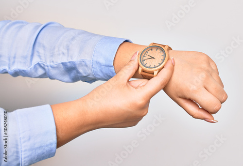 Hand of caucasian young businesswoman wearing wristwatch. Catching watch with two fingers over isolated white background
