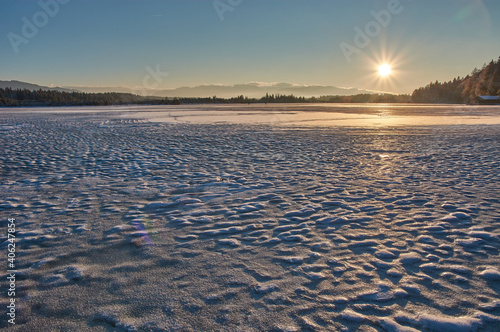 Sunset above a frozen mountain lake in the German alps. Sunset sky above the frozen Kirchsee lake in Bavaria  Germany.