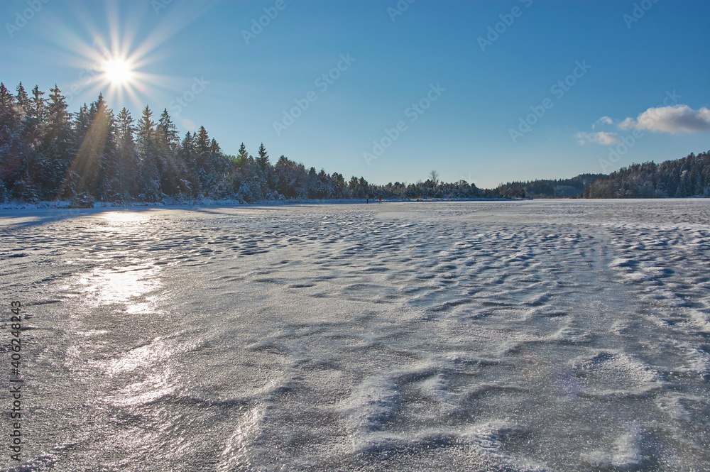 Frozen mountain lake in the sun. Bright sun over a frozen mountain lake in the alps. Frozen mountain lake in the sun. Bright sun over a frozen mountain lake in the alps.