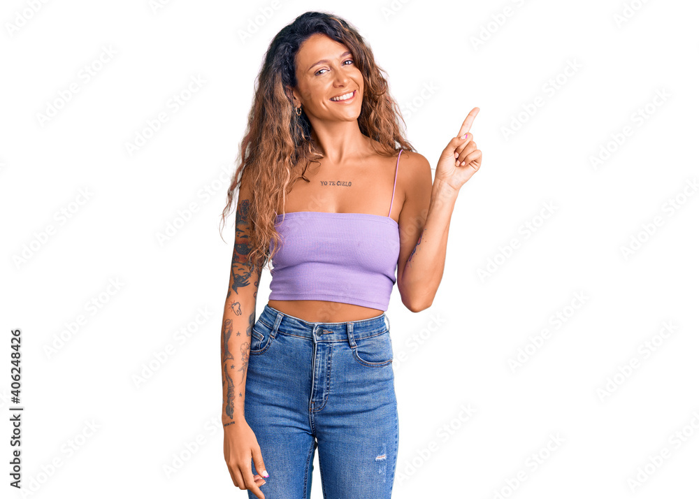 Young hispanic woman with tattoo wearing casual clothes with a big smile on face, pointing with hand finger to the side looking at the camera. Young hispanic woman with tattoo wearing casual clothes with a big smile on face, pointing with hand finger to the side looking at the camera.