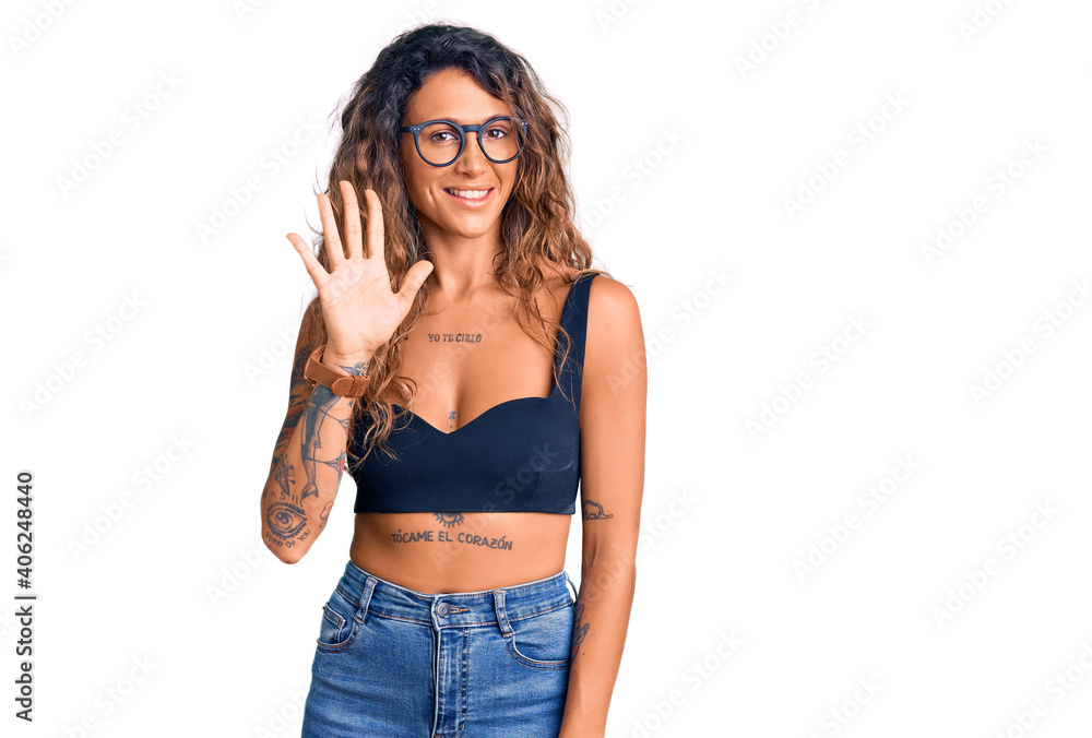 Young hispanic woman with tattoo wearing casual clothes and glasses showing and pointing up with fingers number five while smiling confident and happy. Young hispanic woman with tattoo wearing casual clothes and glasses showing and pointing up with fingers number five while smiling confident and happy.