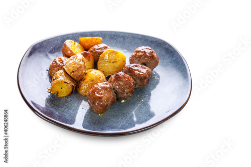 Fried potatoes in uniform and meat cutlets in a plate with greens on a white isolated background.